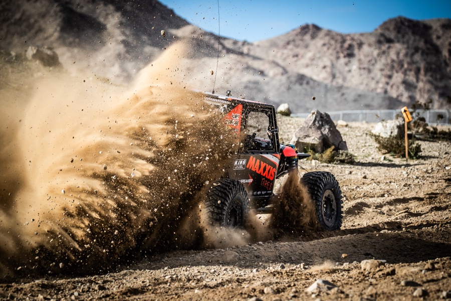 Side-by-side buggy throwing up a spray of dirt and dust on an off-road track